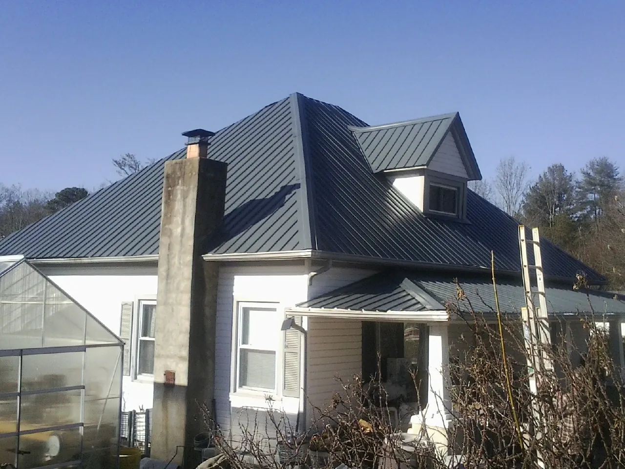 Dark blue standing seam metal roof on a white farmhouse with dormer — Slate & Tile Roof Repair by Roofing Brothers in Forest Falls
