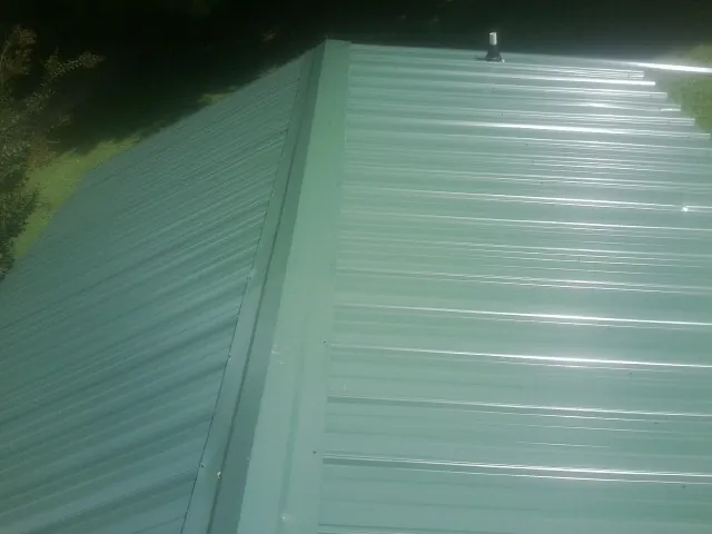 New green metal panels meeting at the ridge of a roof — Flat Roof Repair work by our crew in Forest Falls