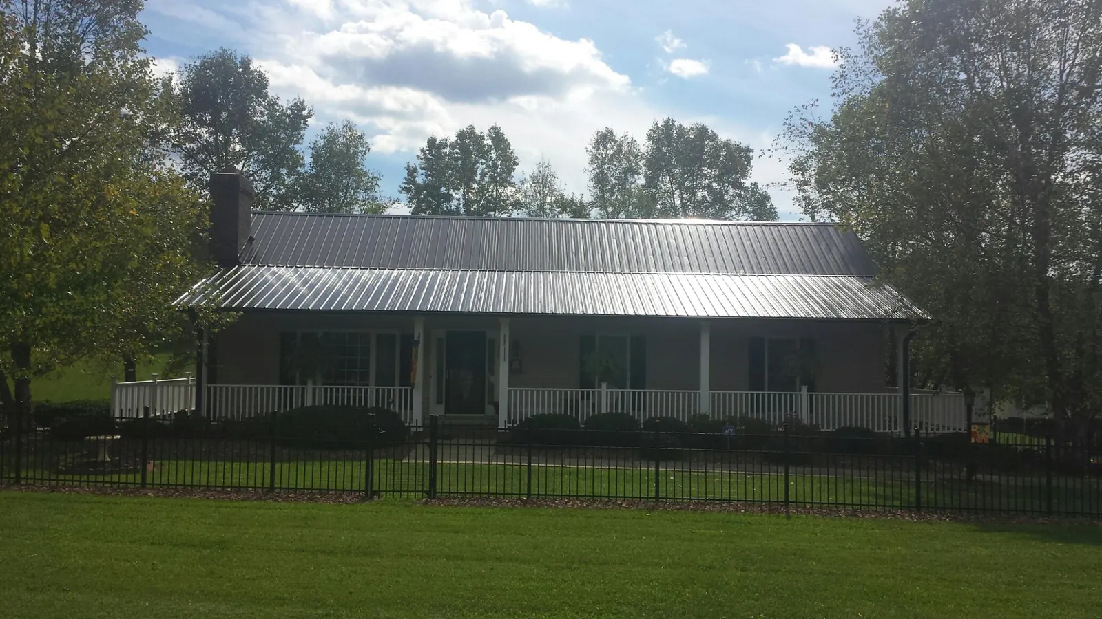 Gray metal roof on a brick ranch with a full width front porch — Gutter Guard Installation work by our crew in Forest Falls