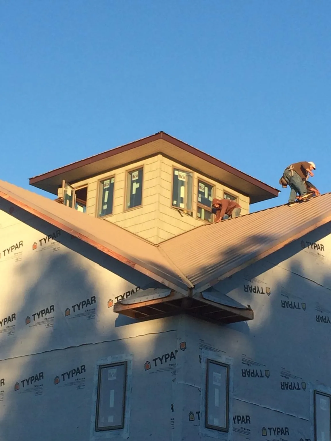 Roofers working around a rooftop cupola on a new metal roof at sunset — Roof Waterproofing in Forest Falls by Roofing Brothers